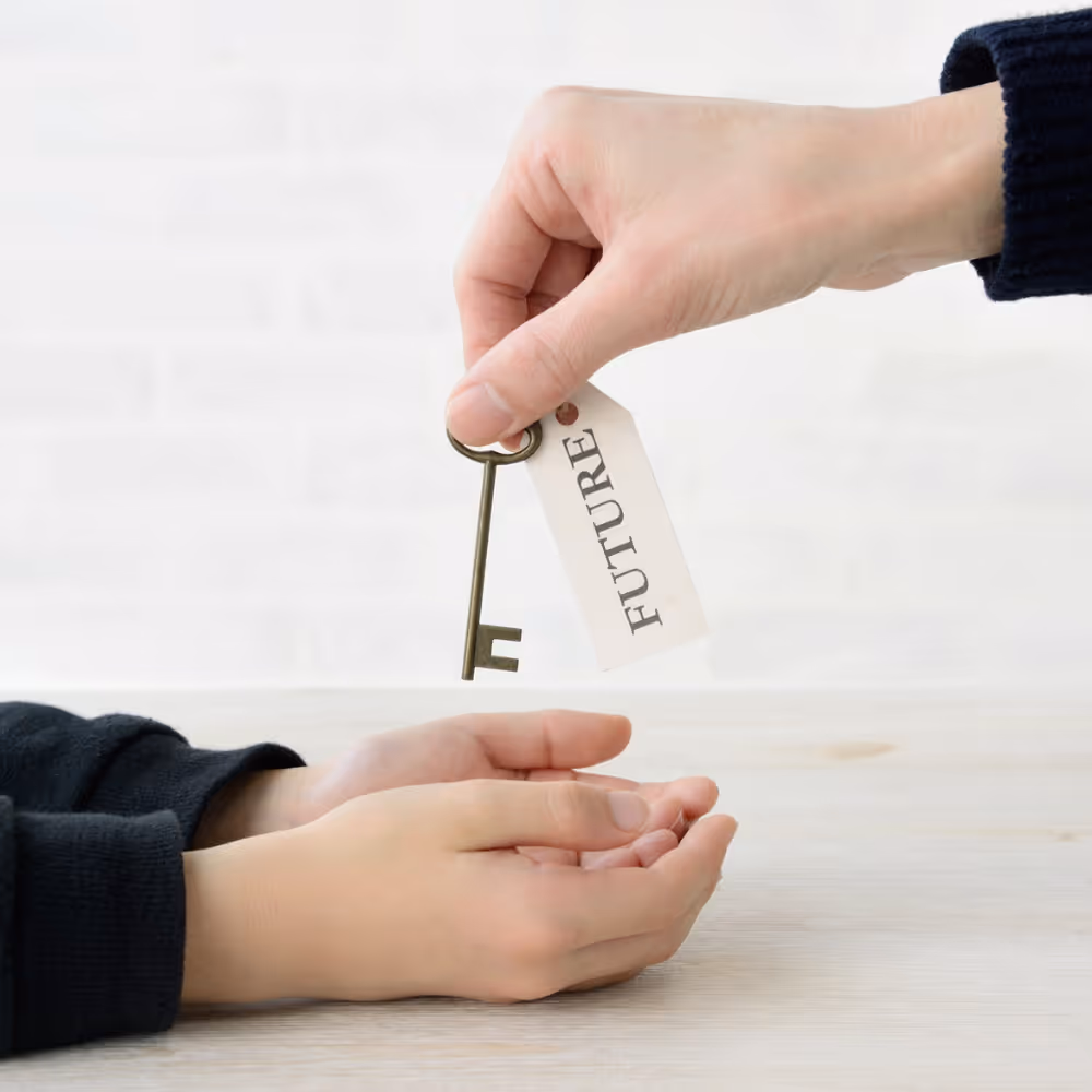 Hand passing a key with a tag labeled 'FUTURE' to another open hand.